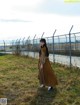 A woman standing in front of a barbed wire fence.