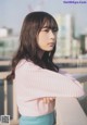 A woman in a pink and white striped shirt leaning against a railing.