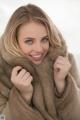 A woman in a fur coat smiles at the camera.