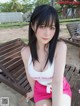 A woman sitting on top of a wooden bench on a beach.