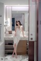 A woman in a white dress standing in front of a mirror.