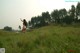 A naked woman standing in a field of tall grass.