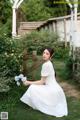 A woman in a white dress sitting on the grass.