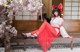 A woman in a red and white outfit sitting on a bench.