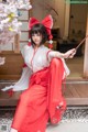 A woman in a red and white kimono sitting on a wooden bench.