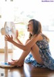 A woman sitting on the floor next to a fan.