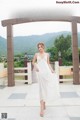 A woman in a white dress standing in front of a sign.