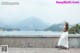 A woman in a white dress standing on a concrete wall.