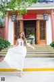 A woman in a white dress standing in front of a building.