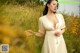 A woman in a white dress standing in a field of yellow flowers.