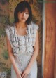 A woman in a white dress standing in front of a wall.