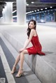 A woman in a red dress sitting on a ledge.