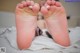 A woman's feet with white nail polish on a bed.