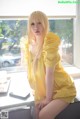 A woman in a yellow dress sitting on a window sill.