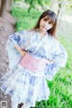 A woman in a blue and pink kimono standing in the grass.