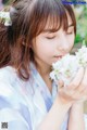 A woman in a kimono holding a bunch of white flowers.