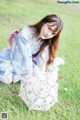 A woman sitting on the grass holding an umbrella.