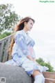 A woman in a blue kimono sitting on a stone wall.