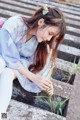 A woman sitting on the steps of a building holding a plant.