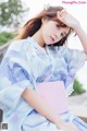 A woman in a blue and pink kimono sitting on a bench.