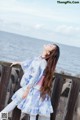 A woman standing on a wooden railing by the water.