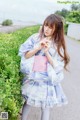 A woman in a blue and pink kimono standing on a road.