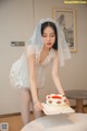 A woman in a wedding dress cutting a cake.