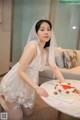 A woman in a wedding dress sitting at a table with a cake.