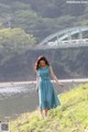 A woman in a blue dress standing by the water.