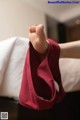 A woman's bare feet in a red bag on a bed.