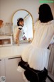 A woman standing in front of a mirror in a kitchen.