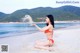 A woman in a red bikini sitting on a beach.