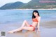 A woman in a red bikini sitting on the beach.