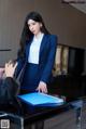 A woman in a blue suit sitting at a desk.