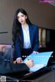 A woman in a business suit sitting at a desk with a laptop.