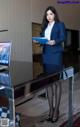 A woman in a blue suit standing in front of a laptop computer.