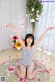 A woman sitting on the floor with her arms outstretched in the air.