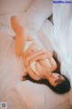 A woman laying on a bed in a white lingerie.