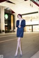 A woman in a business suit standing in front of a Starbucks.