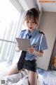 A woman in a blue shirt and black skirt holding a tablet.