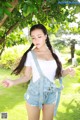 A woman in a white shirt and denim overalls posing for a picture.