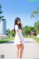 A woman in a white dress standing on a road.