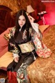 A woman in a kimono sitting on a bed.