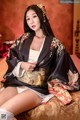 A woman in a kimono sitting on a bed.