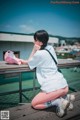 A woman sitting on a wooden bench with a pink bag.