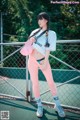 A woman standing on a tennis court holding a pink hat.