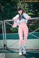 A woman standing on a tennis court holding a pink hat.