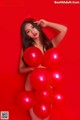 A woman holding a bunch of red balloons.