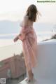 A woman in a pink dress standing on a balcony.