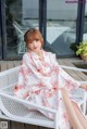 A woman sitting on a white chair wearing a white robe.